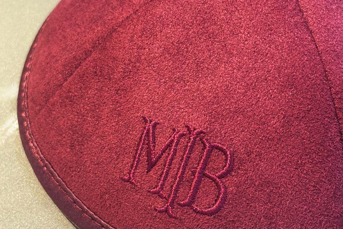 Detalle del monograma bordado en una kippah azul marino de bar mitzvah